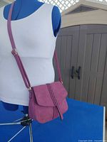 Front view of mauve crossbody purse on mannequin showing flap closure and adjustable strap