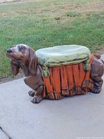 Right side view of painted dachshund statue showing orange drape and green cushion