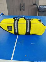 Top view of yellow AKC dog life jacket showing handle, reflective strips, brand patch