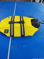 Top view of yellow AKC dog life jacket showing reflective stripes, handle and AKC patch