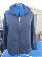 Front view of black hooded rain jacket on dress form