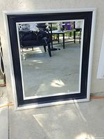 Front view of framed mirror showing silver outer and black inner borders