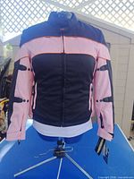 Front view of black and pink motorcycle jacket on stand, tags visible