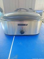Front view of TwoTwelve stainless steel electric roaster with lid on, showing brand badge and control dial