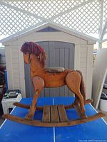 Left side view of full wooden rocking horse on blue table