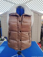 Front view of brown sherpa-lined puffer vest on mannequin