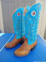 Side view of both boots showing brown foot, teal shaft, stitching, pull holes