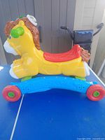 Left side view of yellow VTech ride-on horse on blue base with red wheels