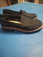 Side view of both loafers showing black faux-suede uppers and lug soles