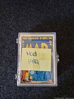 Front of plastic case showing top card with sticky note MAD 1992