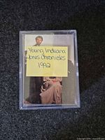Plastic box containing visible Young Indiana Jones Chronicles card on top with handwritten note showing series and year
