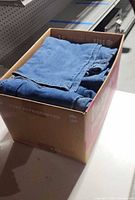 Cardboard box filled with folded blue jeans