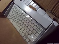 Open carton showing several white keyboards sealed in plastic