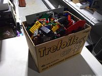 Trefoils cookie box filled with assorted LEGO pieces sitting on table