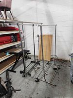 Three chrome garment racks positioned together in storage area