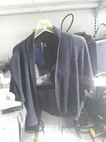 Full view of black open-knit cardigan on hanger