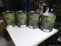 Front view of four paint cans on table