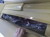 Cardboard box opened showing main metal bar wrapped in plastic