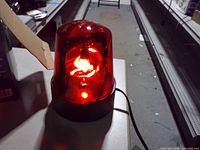 Red beacon lamp plugged in and illuminated on tabletop