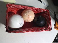 three stone spheres in red basket