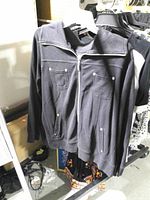 Front view of black zip-up jacket on hanger showing pockets and zipper