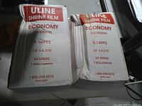 Front view of two Uline shrink film cartons showing product specs and water damage