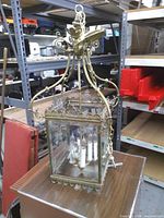 Full view of chandelier showing brass frame, glass panels, candle sockets, chain