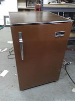 Full view of closed brown Philco Ford Pinto mini-fridge