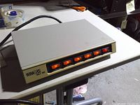 Front view showing six illuminated rocker switches on metal surge protector