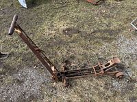 Full view of rusted floor jack with handle extended on ground