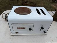 Front view showing enamel body, hot plate, bread slots, crumb tray door and knobs