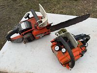 Two gas chainsaws on table