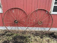Front view of both 54-inch metal wagon wheels leaning against wall