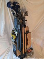 Full view of stand bag with clubs, headcovers and practice balls visible in side pocket