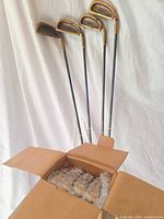 Four unwrapped irons standing and open box with wrapped irons