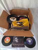 Box containing numerous 7" records, Madonna picture sleeve visible