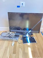 Front view showing Vizio TV, Sony DVD player beneath, remotes, booklet and cables