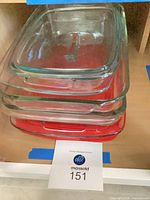 Stack of four glass casserole dishes with red base showing sizes and lid