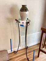 Full view of iron pedestal stand with vase on top