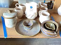 Overview showing lidded jar, chip-and-dip platter, spiral bowl, sauce pourer, six white pitchers