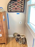 Corner setup showing tapestry on wall and clustered pottery on floor