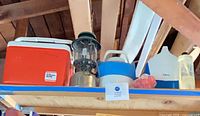 All items on shelf including three coolers, lantern, trays, bottle