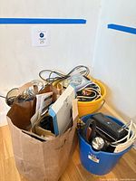 Overall lot with paper bag and two buckets filled with cords and electronics