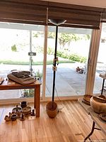 Full view of black torchiere floor lamp standing by window with wicker basket at base