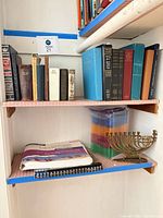Shelf with Judaica books, Thomas Guide, jewel cases, menorah