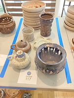 Overview of Shapiro pottery on tabletop, multiple glazed and unglazed pieces visible