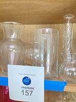 Shelf view showing five assorted clear glass vases