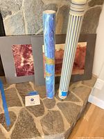 Two matted photographs and two rolled poster tubes on stone hearth