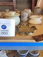 Shelf with nine Robert M Shapiro ceramic pieces, various shapes and glazes