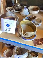 Group view of multiple Robert M Shapiro stoneware pieces on shelf